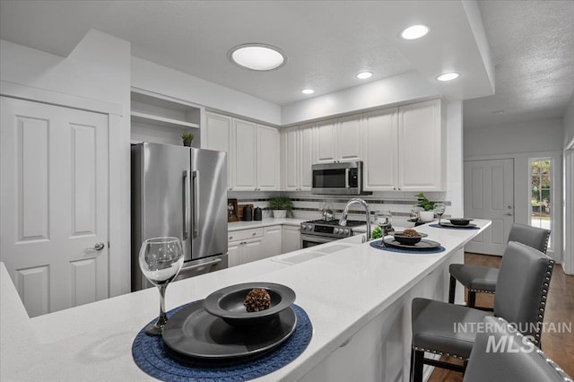 66 W Colchester Dr, Eagle, ID 83616 - kitchen with appliances with stainless steel finishes, a kitchen breakfast bar, a sink, open shelves, and white cabinetry