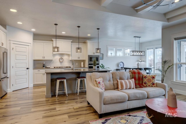 living area with baseboards, light wood-type flooring, and recessed lighting