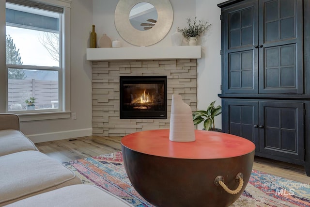 living area featuring a fireplace, baseboards, and wood finished floors