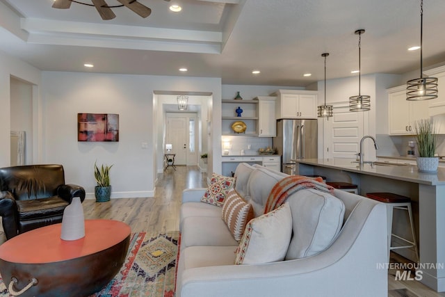 living room featuring a tray ceiling, light wood-type flooring, and recessed lighting