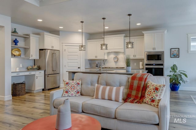 living room with baseboards, light wood-type flooring, and recessed lighting