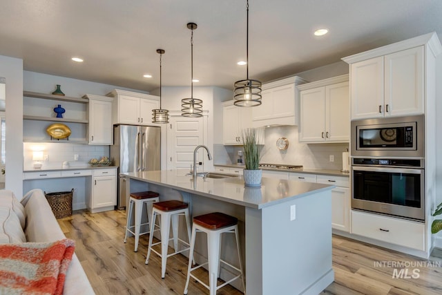 kitchen with light wood finished floors, white cabinetry, stainless steel appliances, and a sink