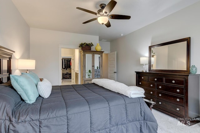 bedroom featuring light carpet, ceiling fan, a closet, and a walk in closet