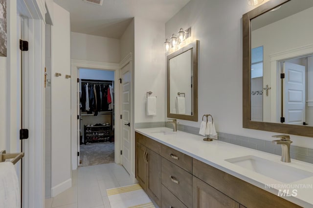 full bath featuring double vanity, tile patterned flooring, a sink, and a walk in closet