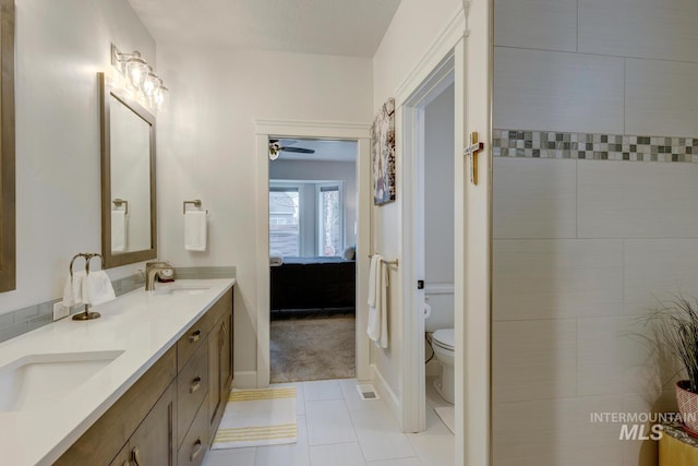 ensuite bathroom with toilet, connected bathroom, a sink, and tile patterned floors