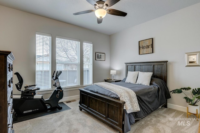 carpeted bedroom with visible vents, baseboards, and a ceiling fan