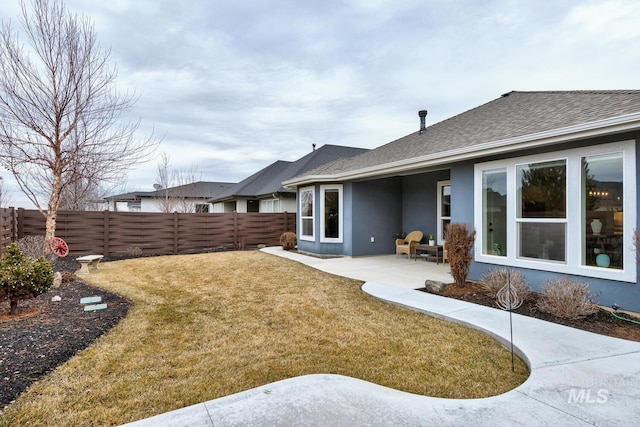 back of property with a patio, a fenced backyard, a yard, roof with shingles, and stucco siding