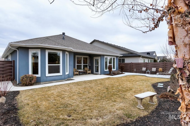 rear view of property featuring a shingled roof, a patio, fence, a yard, and stucco siding