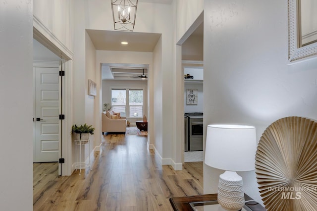 entrance foyer featuring light wood-style flooring, baseboards, and ceiling fan with notable chandelier