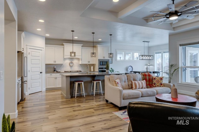 living area with light wood finished floors, ceiling fan, baseboards, and recessed lighting