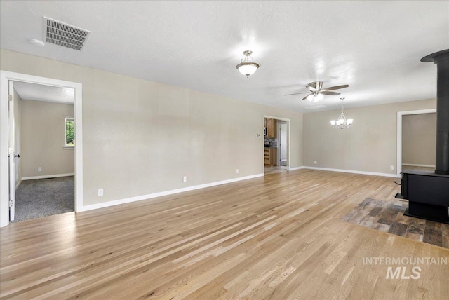 180 E Elmore, Richfield, ID 83349 - unfurnished living room featuring a wood stove, wood finished floors, a ceiling fan, and a chandelier