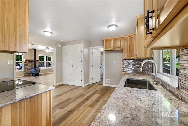 180 E Elmore, Richfield, ID 83349 - kitchen with a wood stove, tasteful backsplash, light stone counters, and light wood-style flooring