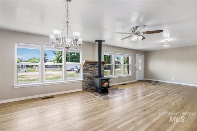 180 E Elmore, Richfield, ID 83349 - unfurnished living room with a wood stove, wood finished floors, a chandelier, and a ceiling fan