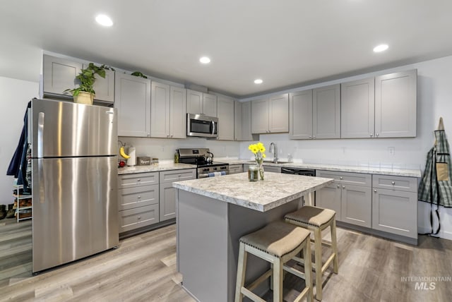 247 Washington St, Gooding, ID 83330 - kitchen featuring stainless steel appliances, gray cabinetry, light countertops, a breakfast bar, and light wood finished floors