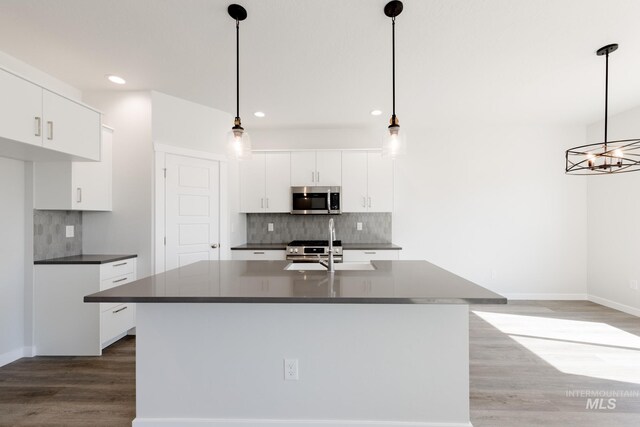 kitchen with stainless steel appliances, hanging light fixtures, light wood-type flooring, sink, and backsplash