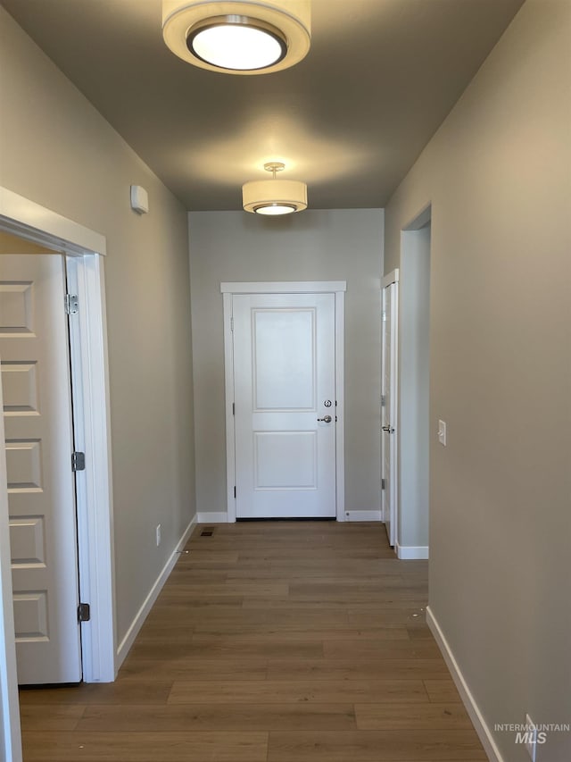 hall with baseboards and wood finished floors