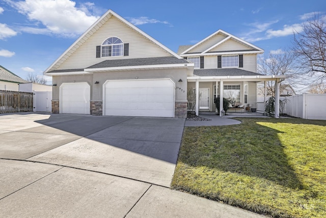 view of front of home featuring a front yard, covered porch, fence, and concrete driveway