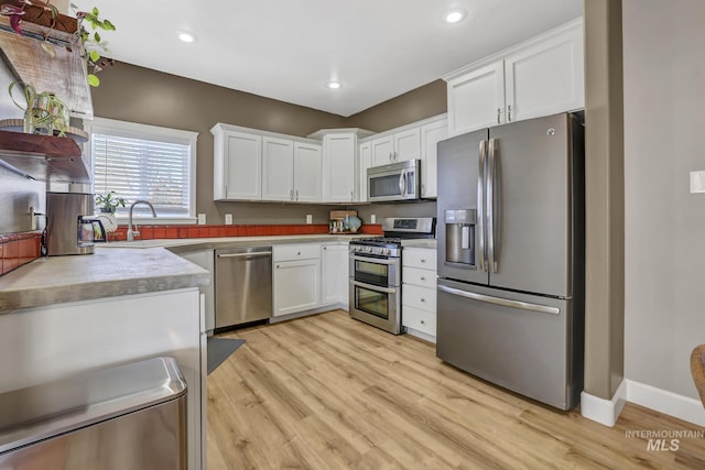 kitchen featuring light wood-style flooring, white cabinetry, stainless steel appliances, and recessed lighting