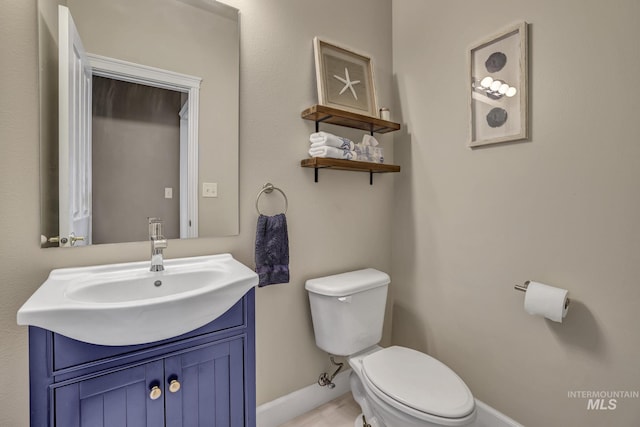 bathroom with toilet, baseboards, and vanity