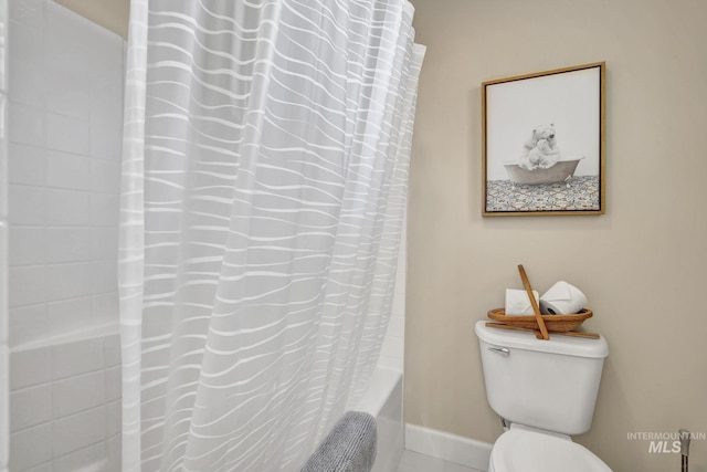 bathroom with shower / bath combination with curtain, toilet, and baseboards