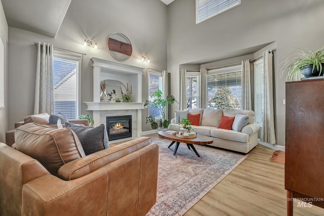 interior space featuring light wood-type flooring, a glass covered fireplace, a wealth of natural light, and baseboards