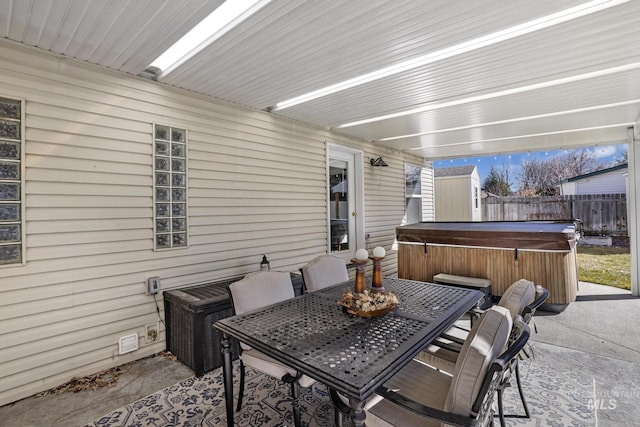 view of patio featuring a hot tub, fence, and outdoor dining space