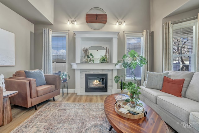 living room featuring a glass covered fireplace, wood finished floors, and baseboards