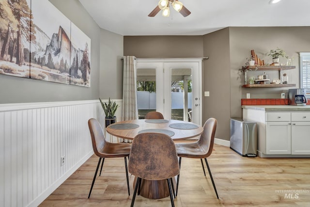 dining area featuring a wainscoted wall, light wood-style flooring, and a ceiling fan