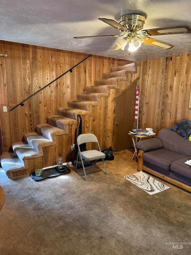 interior space featuring wood walls, ceiling fan, carpet floors, and a textured ceiling