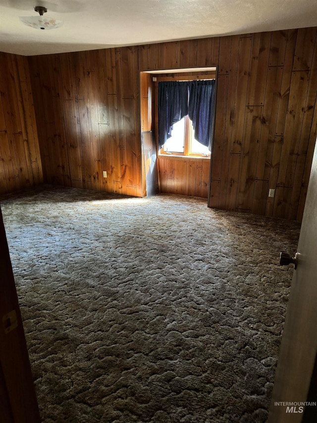 unfurnished room with wood walls and a textured ceiling