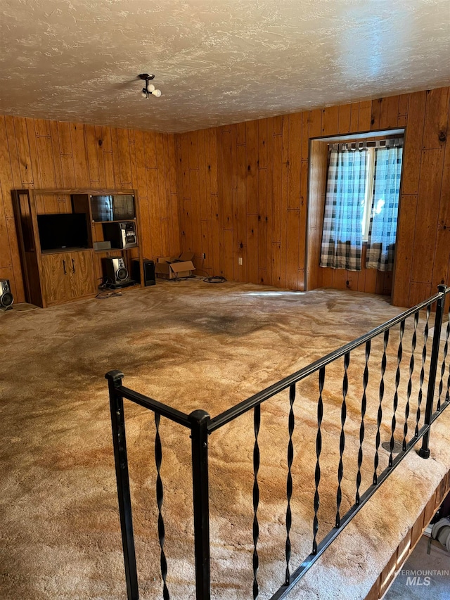 interior space with a textured ceiling and wooden walls