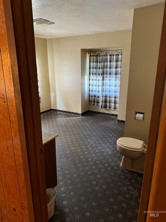 bathroom with a textured ceiling, vanity, and toilet