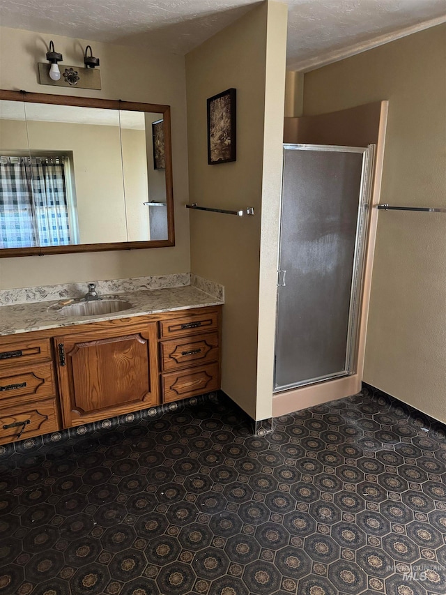 bathroom featuring vanity, a textured ceiling, and an enclosed shower