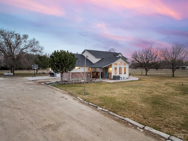 view of front facade with central air condition unit, roof with shingles, a lawn, a garage, and driveway