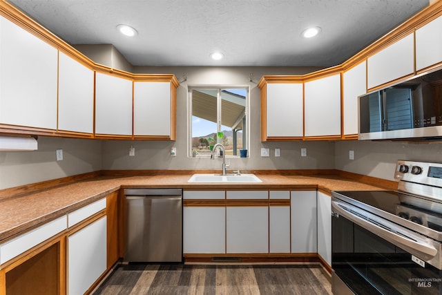 kitchen with a sink, dark wood-style floors, white cabinetry, and stainless steel appliances