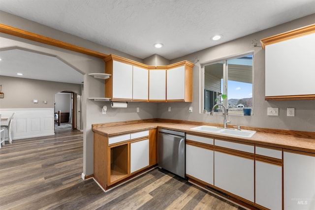 kitchen with a sink, dishwasher, light countertops, arched walkways, and open shelves