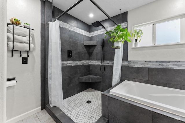 full bathroom featuring a garden tub, baseboards, and tiled shower