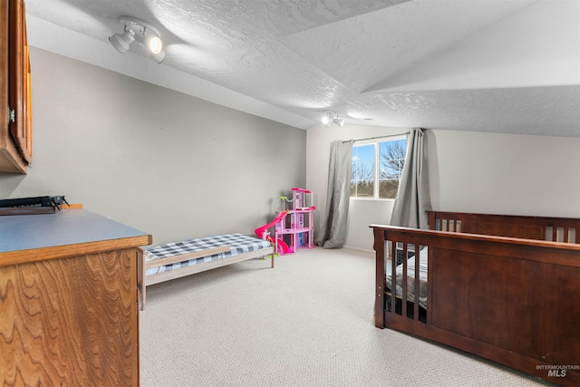 carpeted bedroom with vaulted ceiling and a textured ceiling