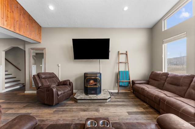 living area with a wood stove, wood finished floors, recessed lighting, baseboards, and stairs