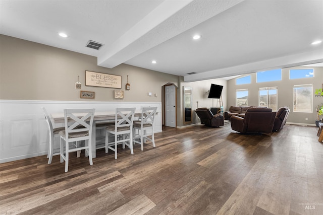 dining space with arched walkways, visible vents, wainscoting, and wood finished floors