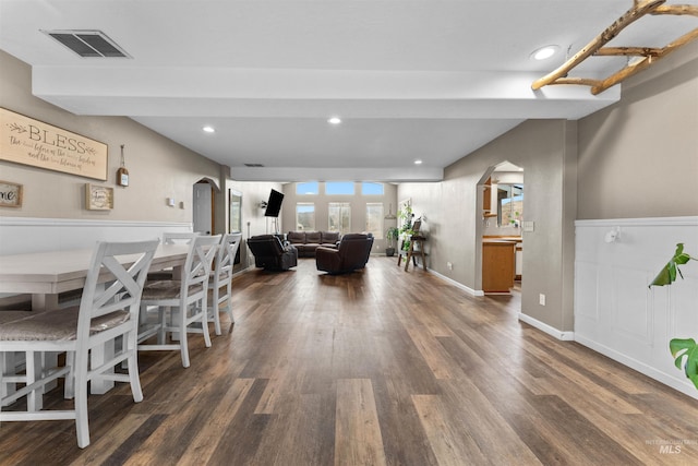 dining space with arched walkways, visible vents, and wood finished floors