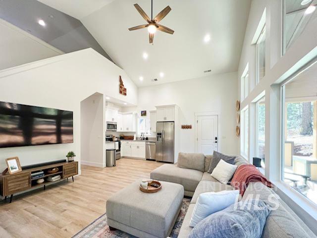 living room featuring recessed lighting, high vaulted ceiling, light wood-type flooring, and ceiling fan