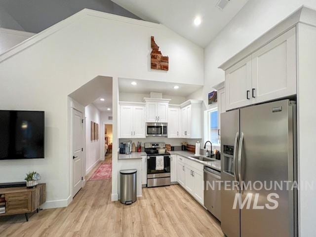 kitchen featuring white cabinetry, stainless steel appliances, light wood-style floors, high vaulted ceiling, and a sink