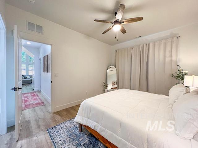 bedroom featuring light wood-style flooring, baseboards, visible vents, and ceiling fan