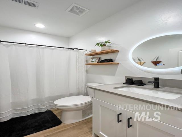 bathroom with visible vents, toilet, vanity, and wood finished floors