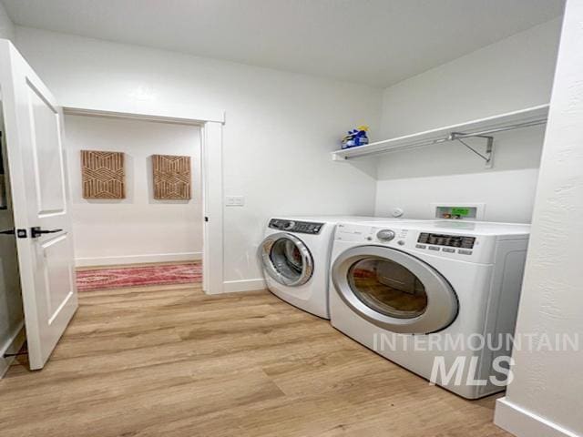 washroom with baseboards, washing machine and clothes dryer, laundry area, and light wood finished floors