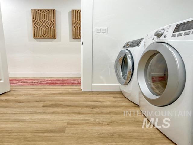 washroom with light wood finished floors, laundry area, independent washer and dryer, and baseboards