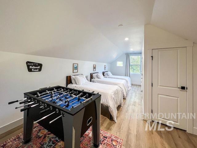 bedroom with light wood-style flooring, baseboards, and lofted ceiling