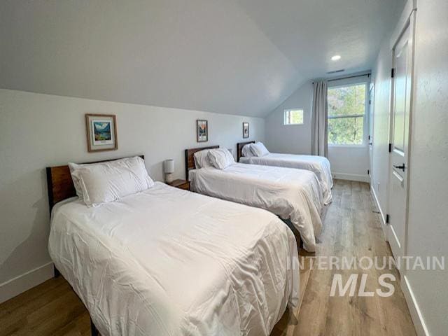 bedroom with vaulted ceiling, light wood-style floors, and baseboards