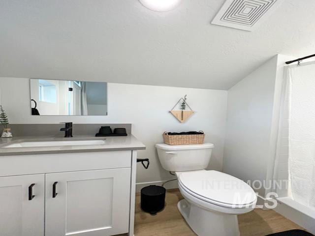 bathroom featuring visible vents, toilet, a shower with shower curtain, vanity, and vaulted ceiling